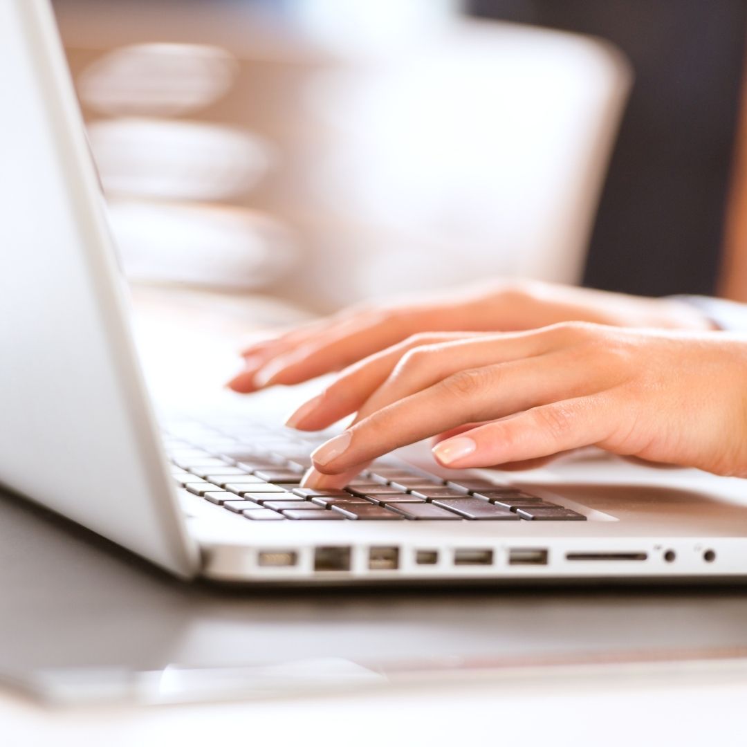 Hands typing on a laptop keyboard.